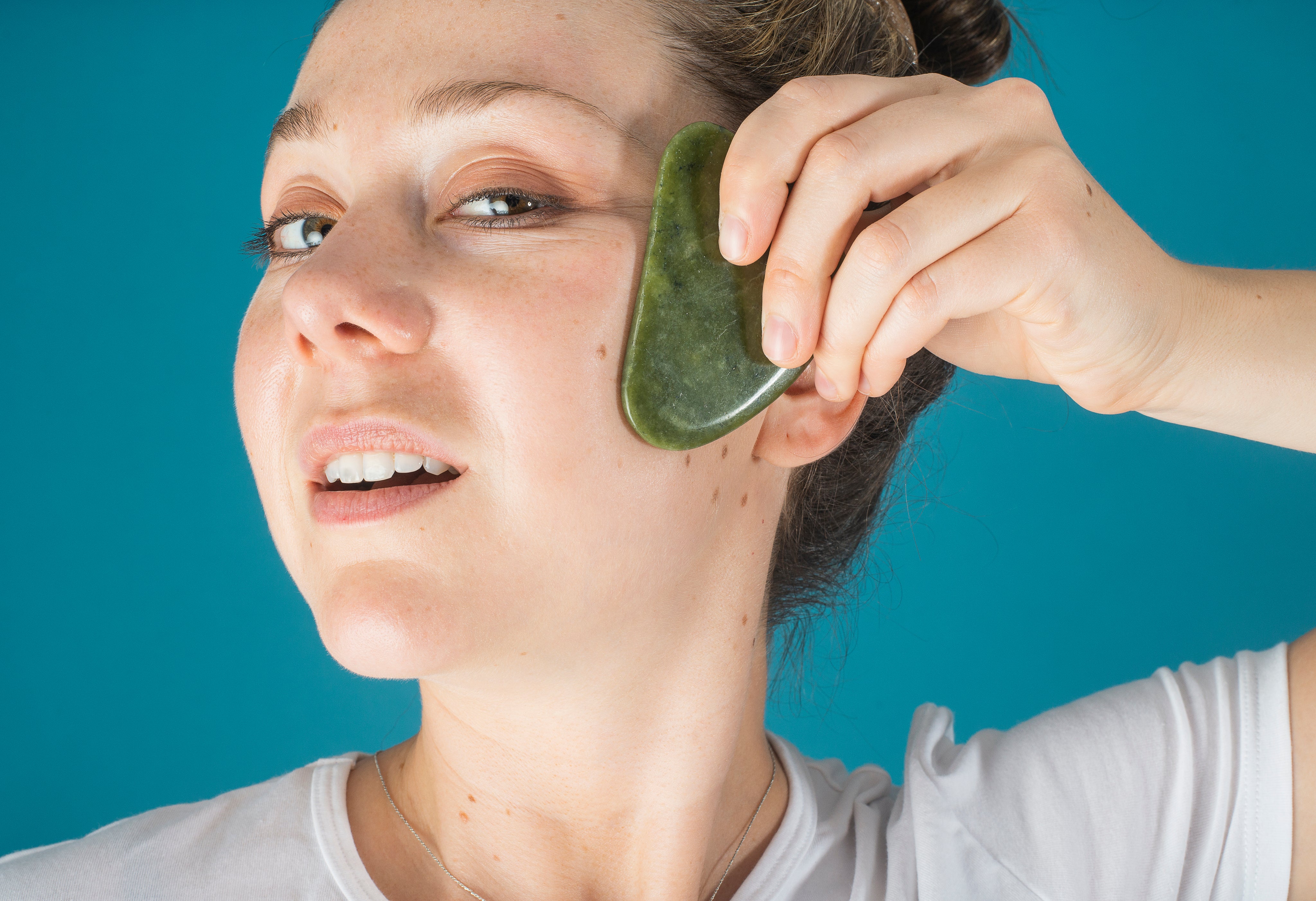 woman-holds-a-jade-face-massager-to-her-face.jpg